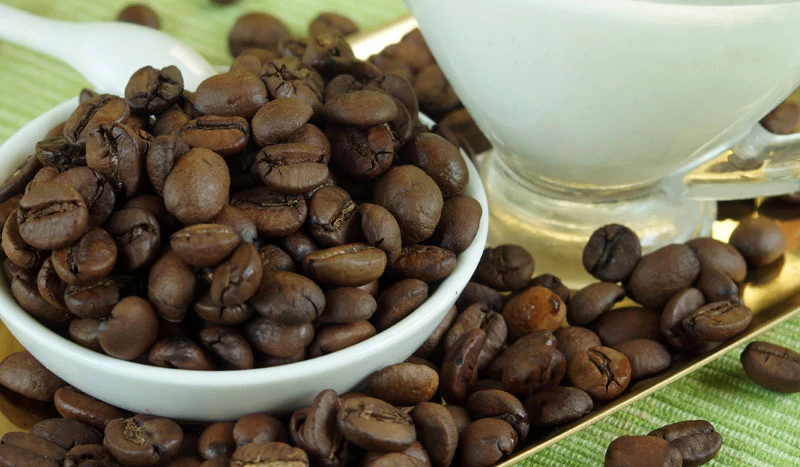 Чашка кофе и зёрна кофе рассыпанные на столе